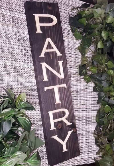 Rustic wooden pantry sign displayed on a pantry door in a farmhouse-style kitchen.
