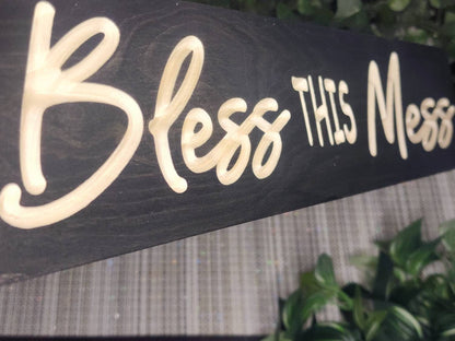 Wooden Bless This Mess sign styled in a rustic kitchen setting.
