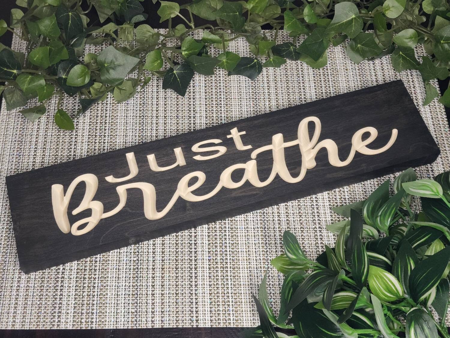 Wooden Just Breathe sign displayed in a serene yoga room setting.
