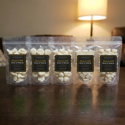 Five clear pouches of cream wax melts in a row on a wood table