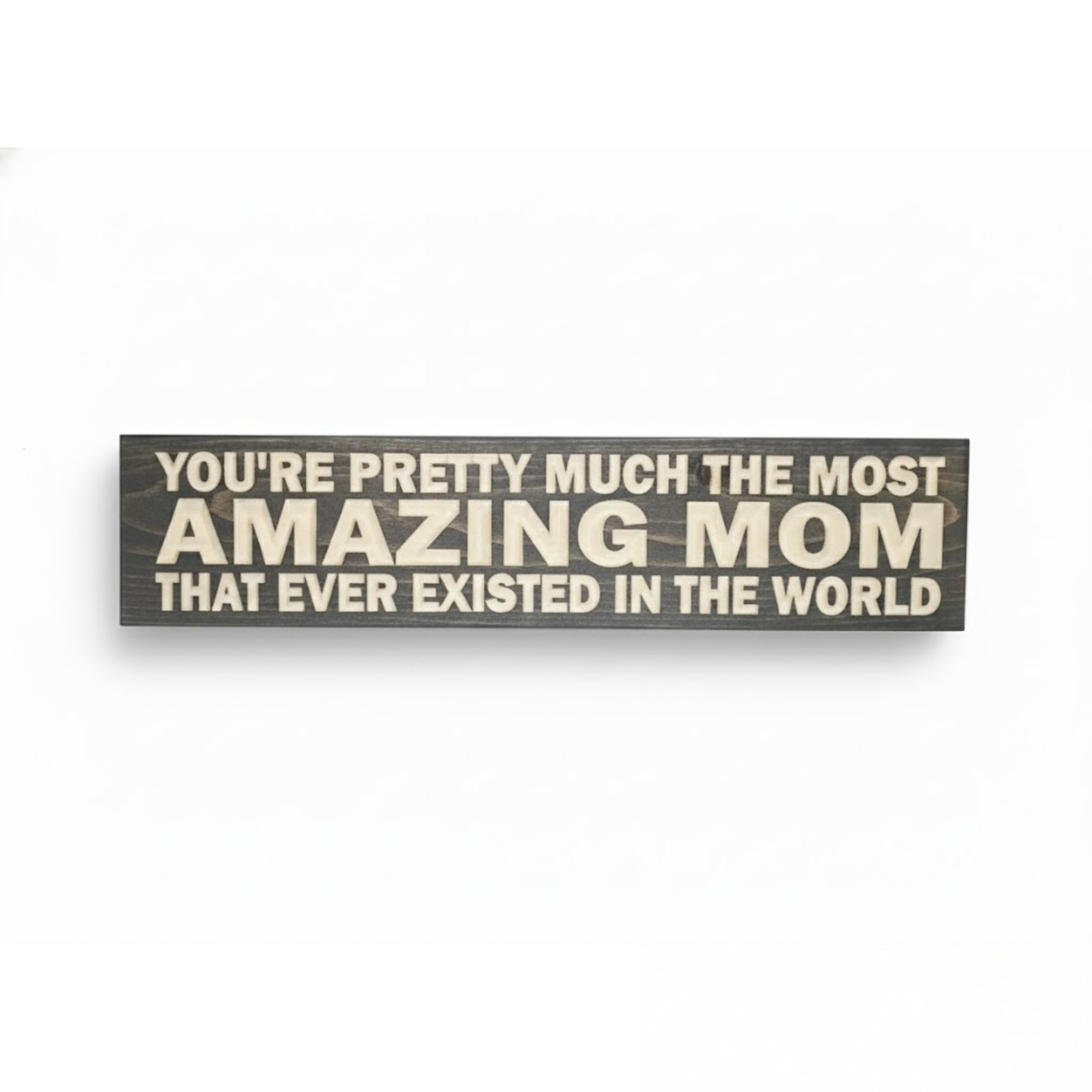 Flat lay view of a grey stained solid wood sign with "Most Amazing Mom" CNC-carved lettering.