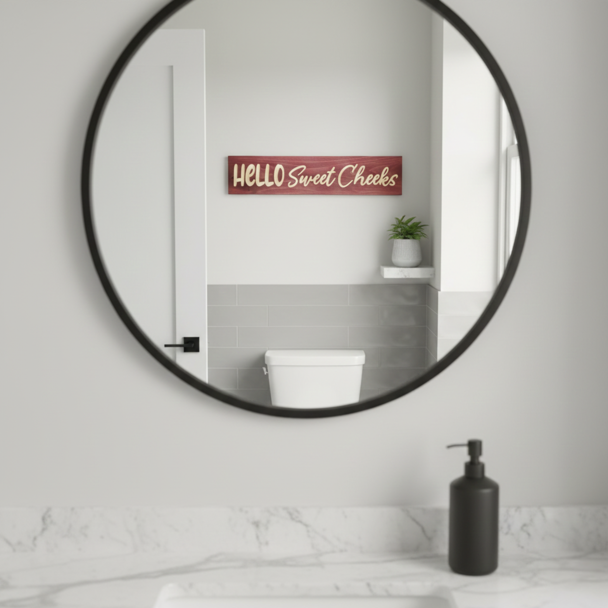 Hello Sweet Cheeks carved wood sign mounted on a bathroom wall as seen through a round vanity mirror reflection.