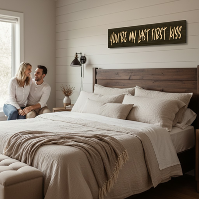 “You’re My Last First Kiss” romantic quote wood sign displayed above a bed in a cozy farmhouse bedroom.