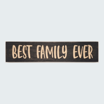 The Best Family Ever Sign, a dark wood plank with light carved letters, is centered on a plain gray background