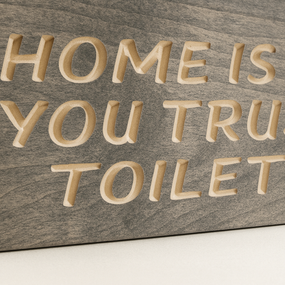 Close-up carved wooden bathroom sign – detailed engraving of “Home Is Where You Trust the Toilet Seat.”