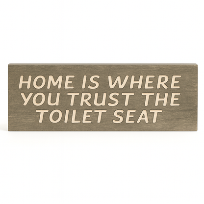 Funny rustic wooden bathroom sign – “Home Is Where You Trust the Toilet Seat” on white background, farmhouse wall décor.