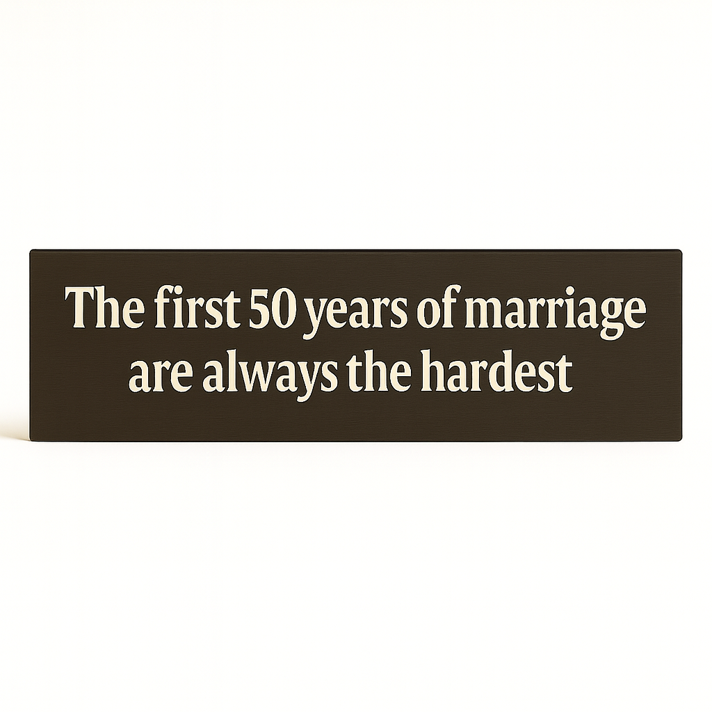 Straight-on studio shot of wooden anniversary sign that reads “The first 50 years of marriage are always the hardest.”