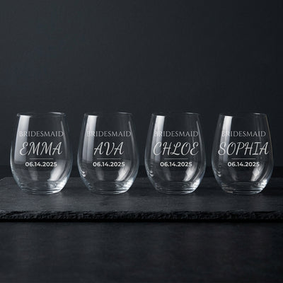 Four engraved bridesmaid wine glasses on dark slate with the etched names lit for contrast