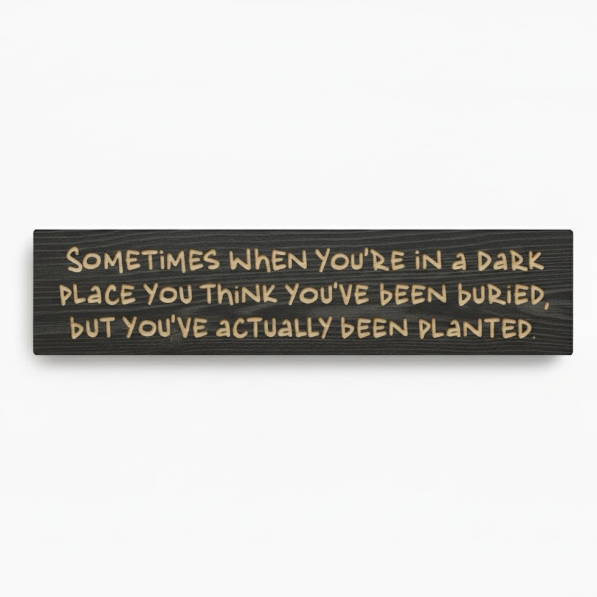 A high-quality product shot of the "Planted Not Buried" carved wood resilience sign in an ebony finish on a clean white background, showing the full inspirational quote.