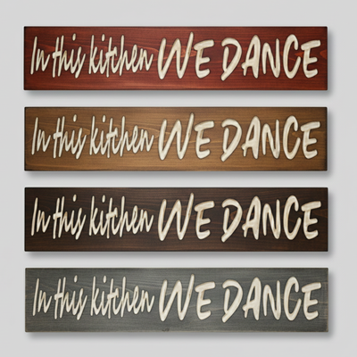 A comparison of four different finish options for the "In This Kitchen We Dance" sign, including dark walnut, cherry, and weathered grey stains on solid wood.