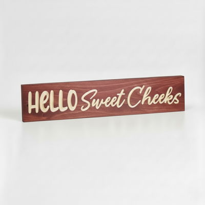 Perspective view of solid wood Hello Sweet Cheeks sign showing deep CNC V-carved lettering and natural wood grain.