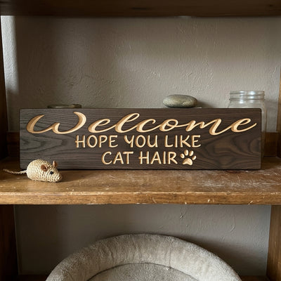 A dark wood Cat House Sign with carved light letters sits on a wooden shelf next to a toy mouse from Bluegrass Gifts