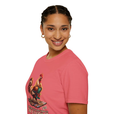 A woman smiles, looking towards the camera, wearing the coral 'Chicken Shirt - Sometimes You Just Have to Say Cluck It' tee in a side profile