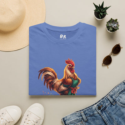 A blue 'Chicken Shirt - Sometimes You Just Have to Say Cluck It' tee is folded flat on a surface with accessories around it