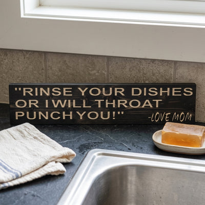 A close-up of the dark wood Clean Up After Yourself Sign on a kitchen counter with a sink and soap, from Bluegrass Gifts