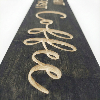 Macro detail shot showing the depth and natural wood grain of the V-carved letters on a Bluegrass Gifts coffee sign.