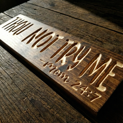 Detailed close-up shot highlighting the deep CNC V-carving texture and natural wood grain contrast on the "Thou Shalt Not Try Me" sign.