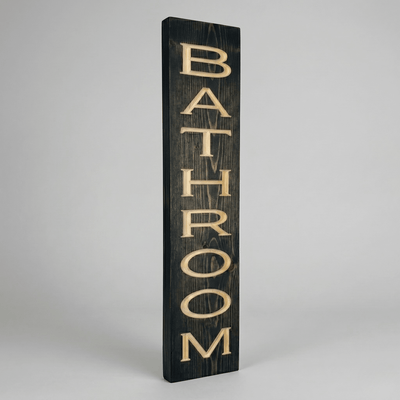 Side angle view of the vertical bathroom wood sign showing dimensional CNC carved letters and solid wood thickness in dark ebony stain finish.
