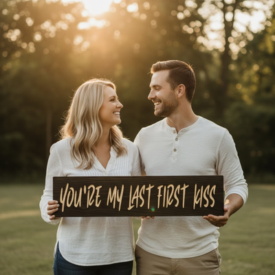 Smiling couple holding the “You’re My Last First Kiss” carved wood sign—handmade romantic gift, USA made.
