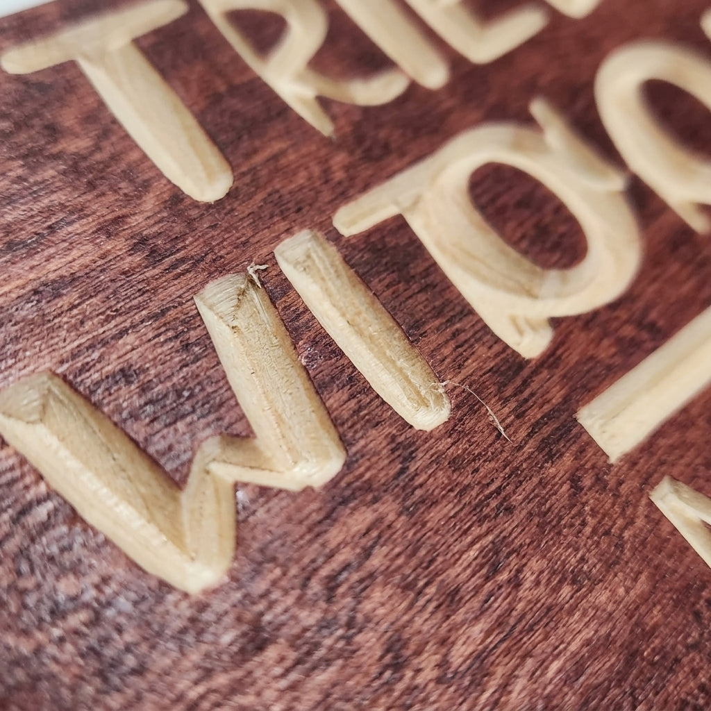 Close-up detail of the carved letters "WITHOUT" on the Coffee Sign, showing the light wood grain and texture