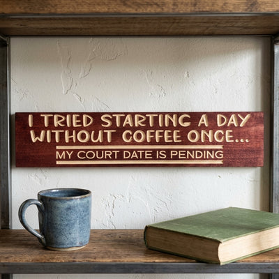A carved wood Coffee Sign "I tried starting a day without coffee once... My court date is pending" on a shelf with a mug and book from Bluegrass Gifts
