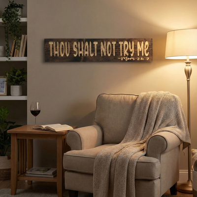 Rustic "Thou Shalt Not Try Me" wooden sign hanging above a cozy armchair with a book and wine, perfect for a mom cave or reading nook.