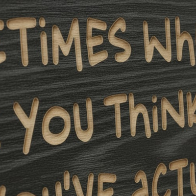A close-up detail shot of a CNC carved wood sign, showing the deep, three-dimensional texture of the inspirational quote and the natural grain of the solid wood with an ebony finish.