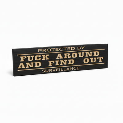 Angled view of the “Protected by Fuck Around and Find Out” wooden surveillance sign, CNC-carved and finished in black.
