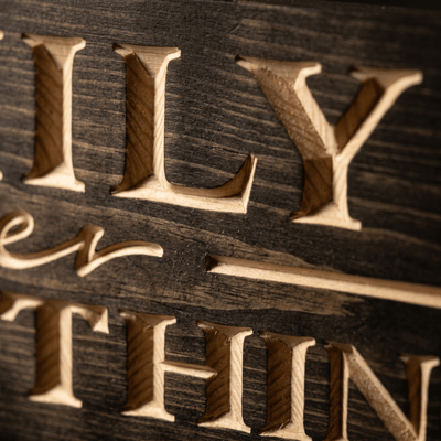 Close-up macro of deeply CNC-carved letters on the Family Over Everything solid wood sign showing dimensional 2.5D routing and natural grain