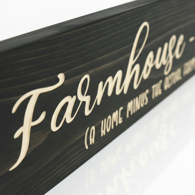 Close-up macro view of a "Farmhouse-ish" wood sign showing the 0.125-inch deep CNC carved lettering recessed into the dark stained poplar grain. Hand-finished in Rineyville, Kentucky by Bluegrass Gifts.