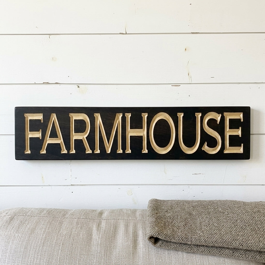 A black Farmhouse Sign with carved light wood letters hangs on a white shiplap wall, above a sofa from Bluegrass Gifts