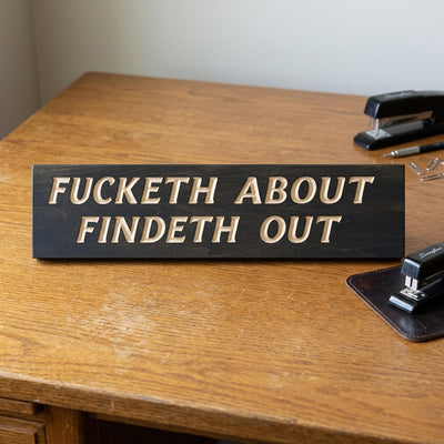 A dark wood Medieval FAFO Sign sits on a light brown desk next to office supplies from Bluegrass Gifts