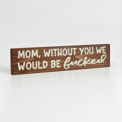 An angled view showing the 3D relief of the carved lettering on a Bluegrass Gifts wooden sign that reads "Mom Without You We Would Be Fucked."