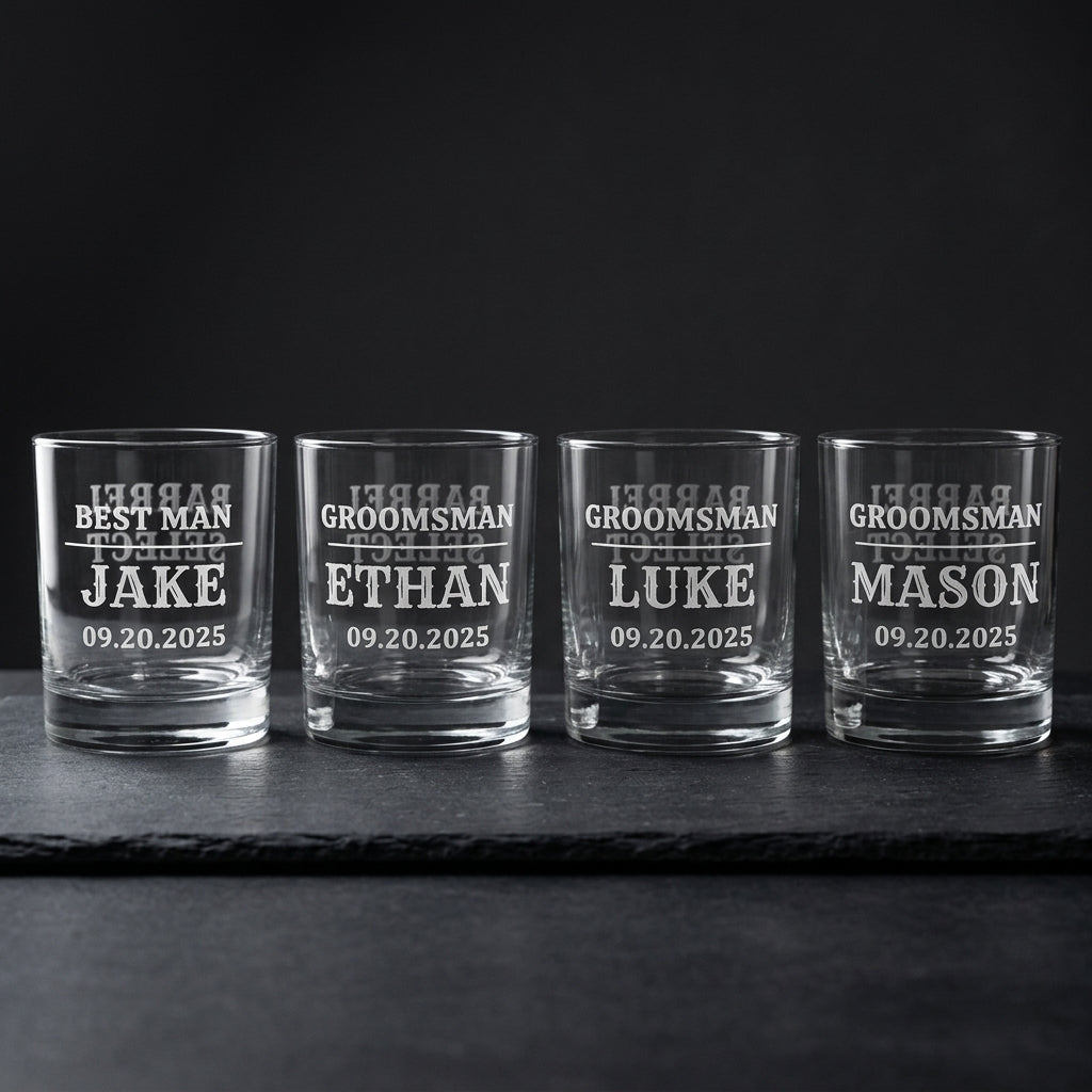 Four personalized groomsmen whiskey glasses on dark slate, Barrel Select engraving visible through the glass