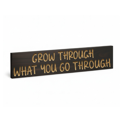 Angled product photo showing the thickness and grain of the carved solid‑wood “Grow Through What You Go Through” sign.