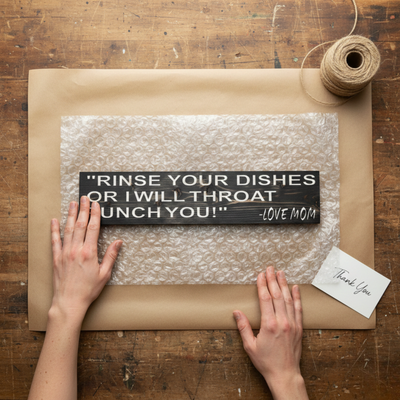 The "Rinse Your Dishes Or I Will Throat Punch You!" sign being carefully packaged with bubble wrap and a thank you card.
