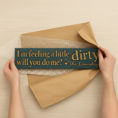 A pair of hands carefully packaging a handmade carved wood sign, showing the quality craftsmanship of a Bluegrass Gifts product.