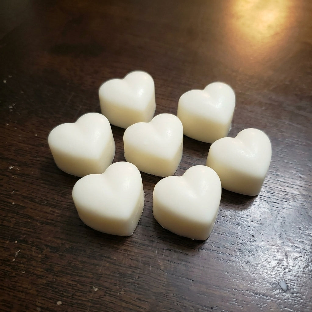 A small group of cream heart wax melts on a dark wood table