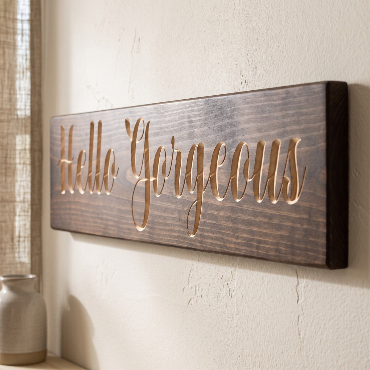 Close-up of the carved letters on the Hello Gorgeous sign, natural pine inside the cuts against the stained grain