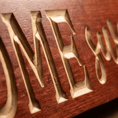 Macro close-up of CNC carved ME letters and script lettering on the Home Sweet Home wood sign revealing real pine grain, hand-finished depth, and authentic Kentucky craftsmanship.