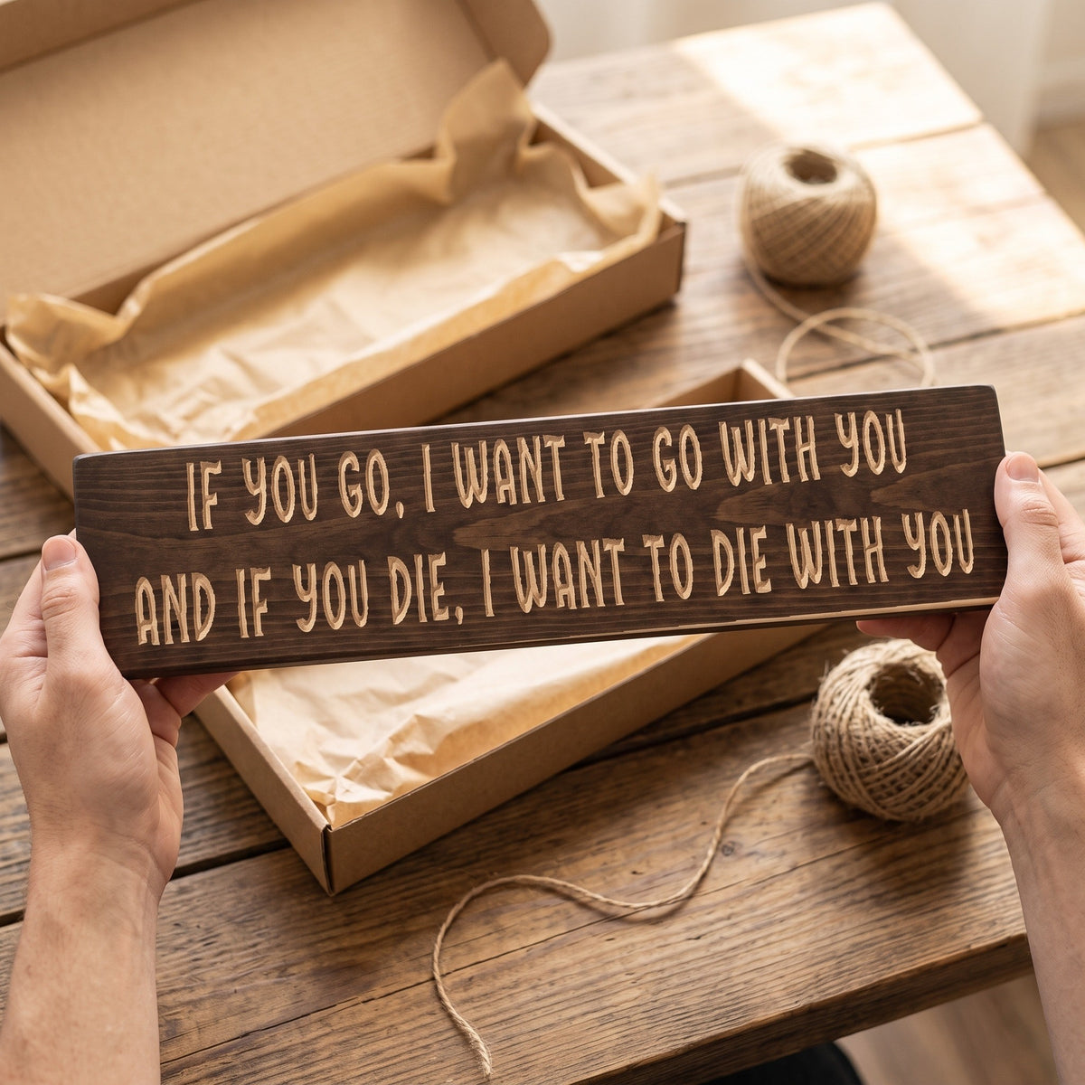 Hands holding the If you go, I want to go with you, and if you die, I want to die with you sign over a kraft gift box with tissue paper