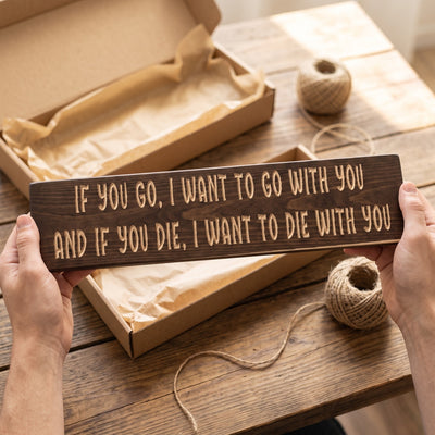 Hands holding the If you go, I want to go with you, and if you die, I want to die with you sign over a kraft gift box with tissue paper