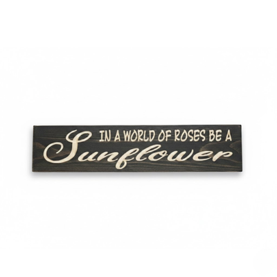 Straight-on hero shot of the In a World of Roses Be a Sunflower carved wood sign featuring high-contrast white lettering on a dark walnut finish by Bluegrass Gifts.