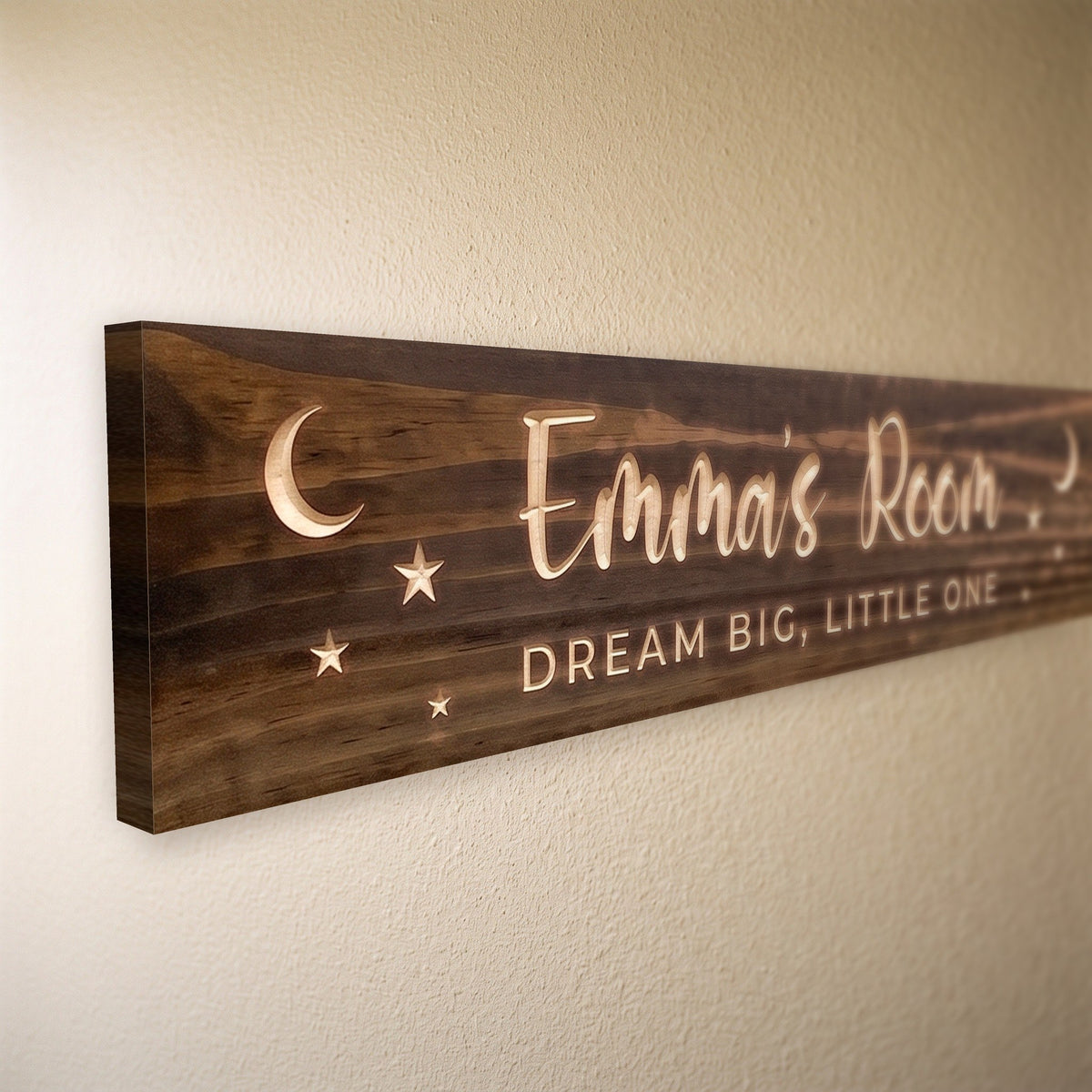 Close-up of the carved letters on the Emma's Room sign, natural pine inside the cuts against the stained grain