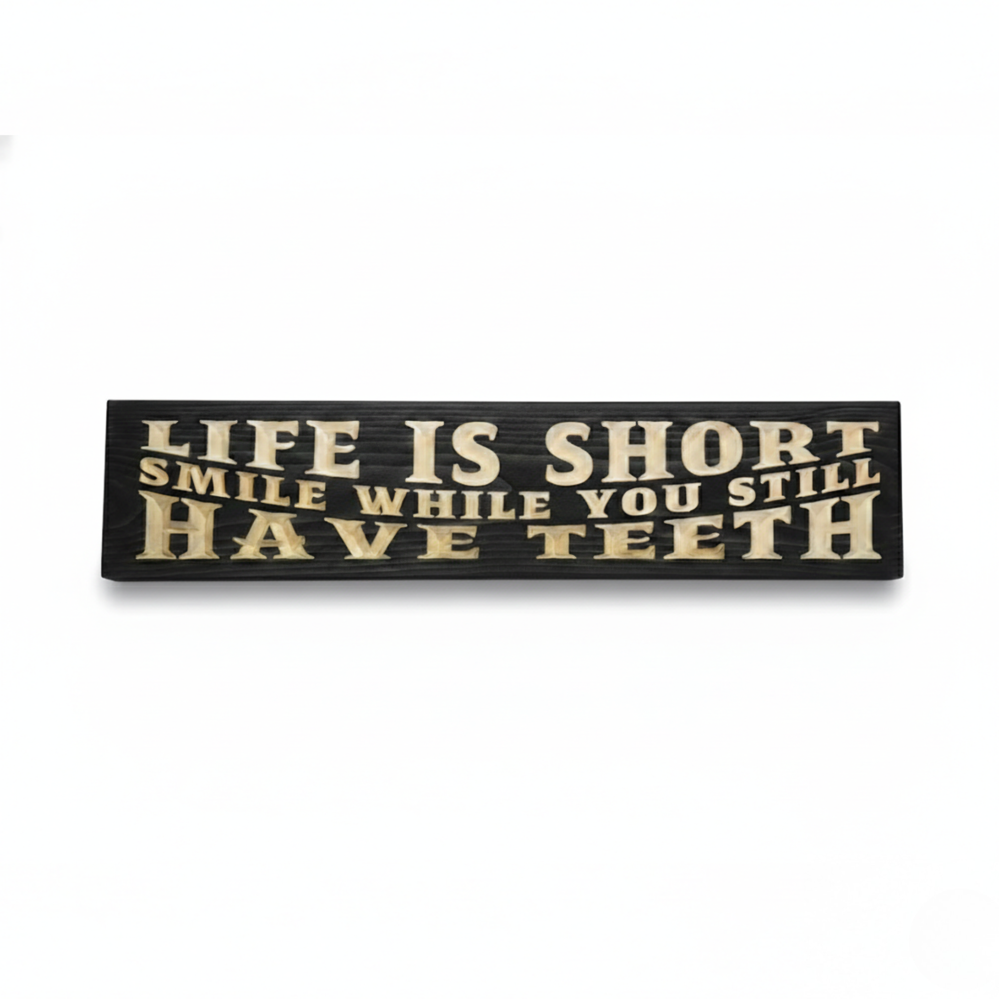 High-contrast black wooden sign with deeply carved text "Life Is Short Smile While You Still Have Teeth" in natural wood grain, centered view.