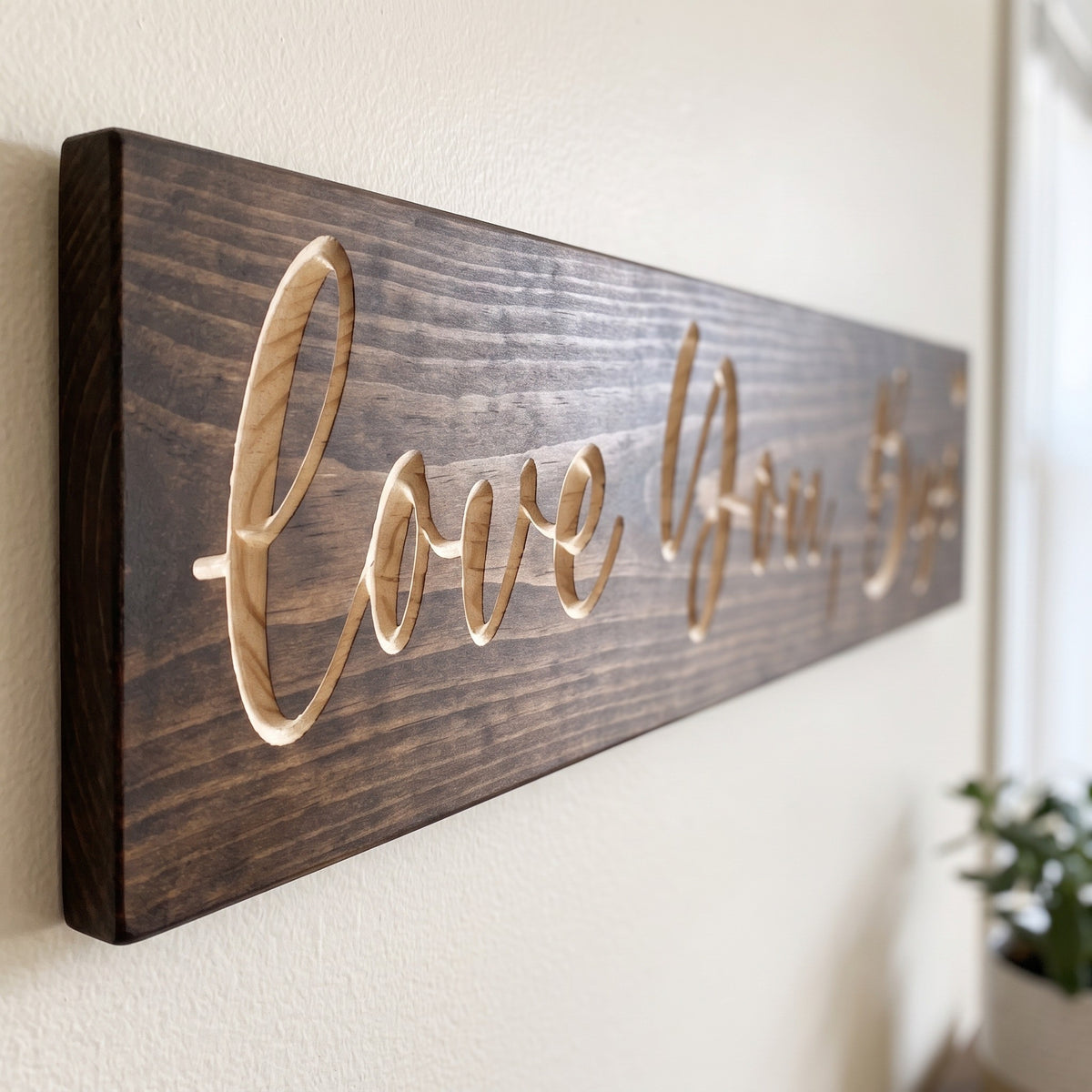 Close-up of the carved letters on the Love You, Bye sign, natural pine inside the cuts against the stained grain