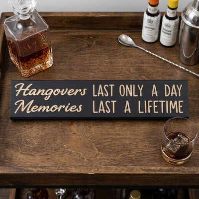 An overhead view of the Man Cave Sign on a wooden bar cart with a decanter, bottles, and a glass of ice from Bluegrass Gifts