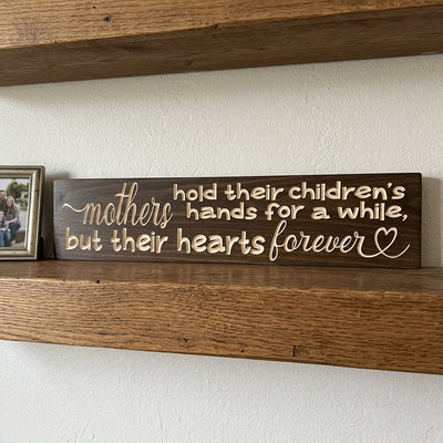 A close-up of the Meaningful Wall Art sign on a wooden shelf, showing the carved quote and a small framed photo from Bluegrass Gifts