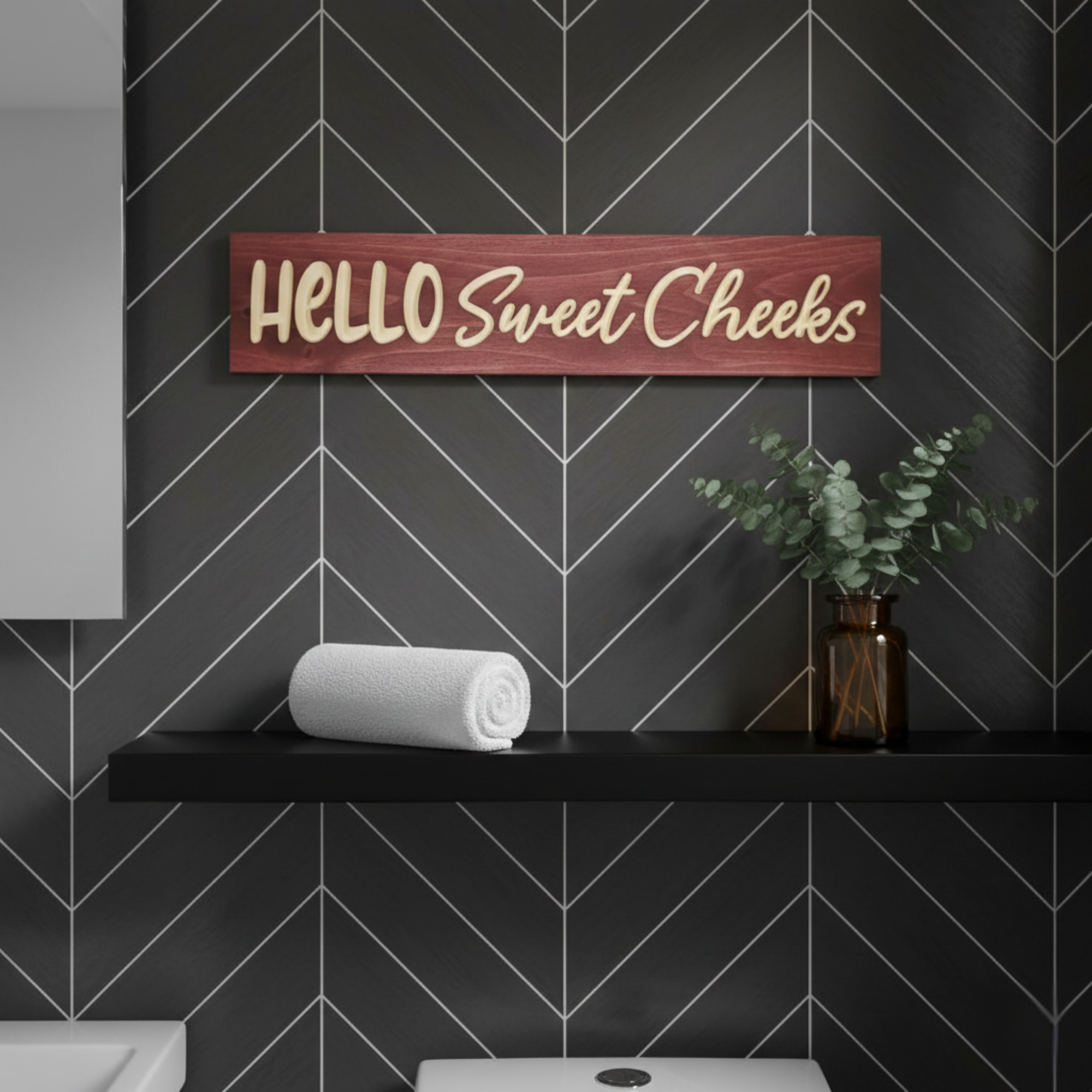 Bluegrass Gifts Hello Sweet Cheeks wood sign displayed on a black floating bathroom shelf with modern chevron tile.