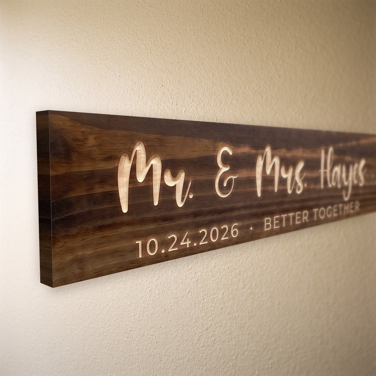 Close-up of the carved letters on the Mr. & Mrs. Hayes sign, natural pine inside the cuts against the stained grain